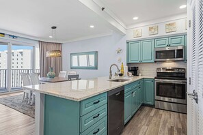 Une cuisine moderne avec des armoires de couleur turquoise, des appareils électroménagers en acier inoxydable et un grand îlot central.
