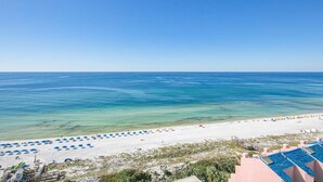 A beach with umbrellas and a building with a blue roof. - Exclusive Gulf Views, Private Balcony (Miramar Beach)