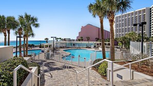 Ein Resort mit Poolbereich, Palmen und Meerblick.
