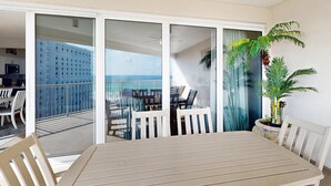 Ein Balkon mit Tisch und Stühlen, einem Blumentopf und Blick aufs Meer.