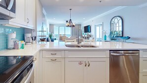 Una cocina moderna con armarios blancos, electrodomésticos de acero inoxidable y una isla grande con fregadero.