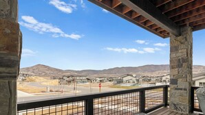A covered outdoor area with a view of a residential neighborhood, stone pillars, and a stop sign. - Mayflower Lakeside 104 | Reservoir + Mountain View | Full Kitchen | Private Bedrooms (Heber City)