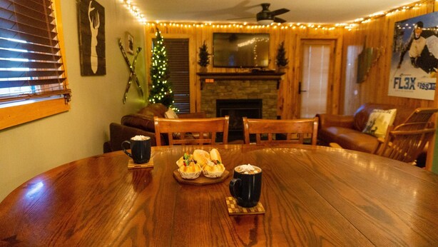 Une table à manger en bois, avec un sapin de Noël et une cheminée.