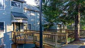 Un bâtiment à deux étages doté d’une terrasse en bois et d’un escalier menant à l’étage supérieur.