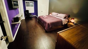 Une chambre à coucher avec un lit, une chaise, une télévision et une lampe.