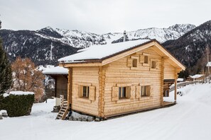 Puinen mökki, jossa on kalteva katto, pieni kuisti ja portaat, jotka johtavat sisäänkäynnille.