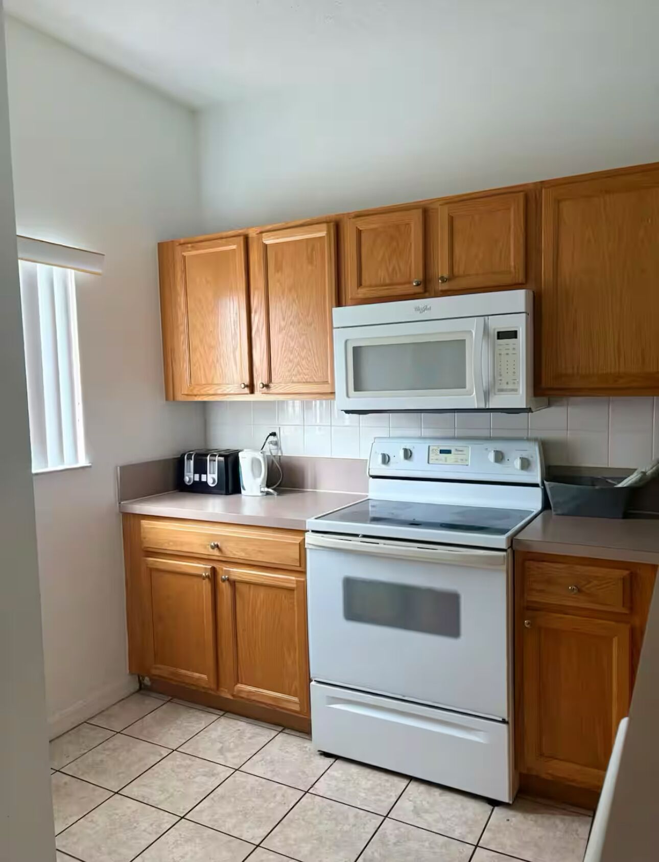 A kitchen with wooden cabinets, a white microwave, and a stove.