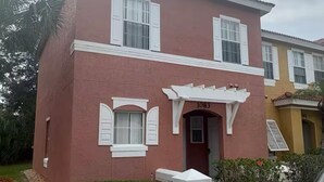 A two-story house with a red facade, white shutters, and a number '1083' on the front door. - Home in Kissimmee near Disney and Universal (Kissimmee)