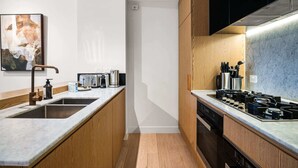 Una cocina moderna con armarios de madera, un lavamanos de acero inoxidable, una estufa a gas y una encimera con varios electrodomésticos.