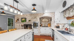Une cuisine moderne avec des meubles blancs, un mur en briques et un grand îlot central.