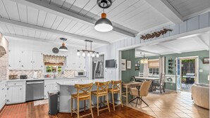 Une cuisine spacieuse avec des meubles blancs, un îlot central en bois et un coin repas avec des chaises.