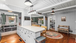 Une cuisine spacieuse dotée d’un îlot central, de planchers en bois et de luminaires suspendus.