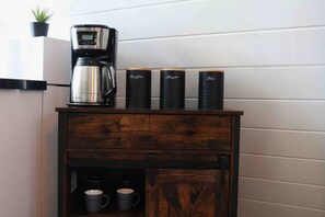 A coffee maker on a wooden cabinet with three containers labeled coffee, sugar, and tea. - Pepe's Village Luxury Aqua Dream Villa (Rincón)