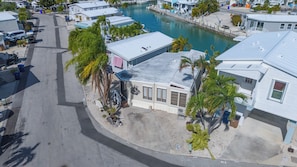 A residential area with a marina, houses with metal roofs, and palm trees. - Ground Level Waterfront 2BR in Venture Out - 23' Seawall, Pool, Marina & Pet Friendly (Cudjoe Key)
