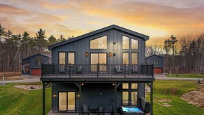 Ein modernes, zweistöckiges Haus mit Balkon, großen Fenstern und einem Whirlpool im Garten.