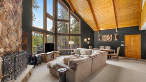 Un salón espacioso con un sofá seccional grande, una chimenea y ventanas amplias que ofrecen vistas al exterior.