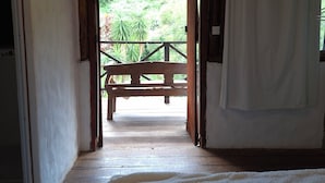 A corridor leading to an outdoor area with a wooden bench and a view of greenery. - Hotel fazenda casa mato  (Taubate)
