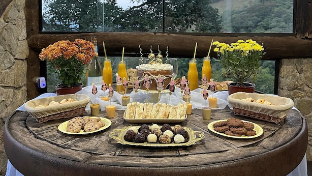 A table with a variety of desserts and drinks, set against a scenic outdoor view. - Hotel fazenda casa mato  (Taubate)