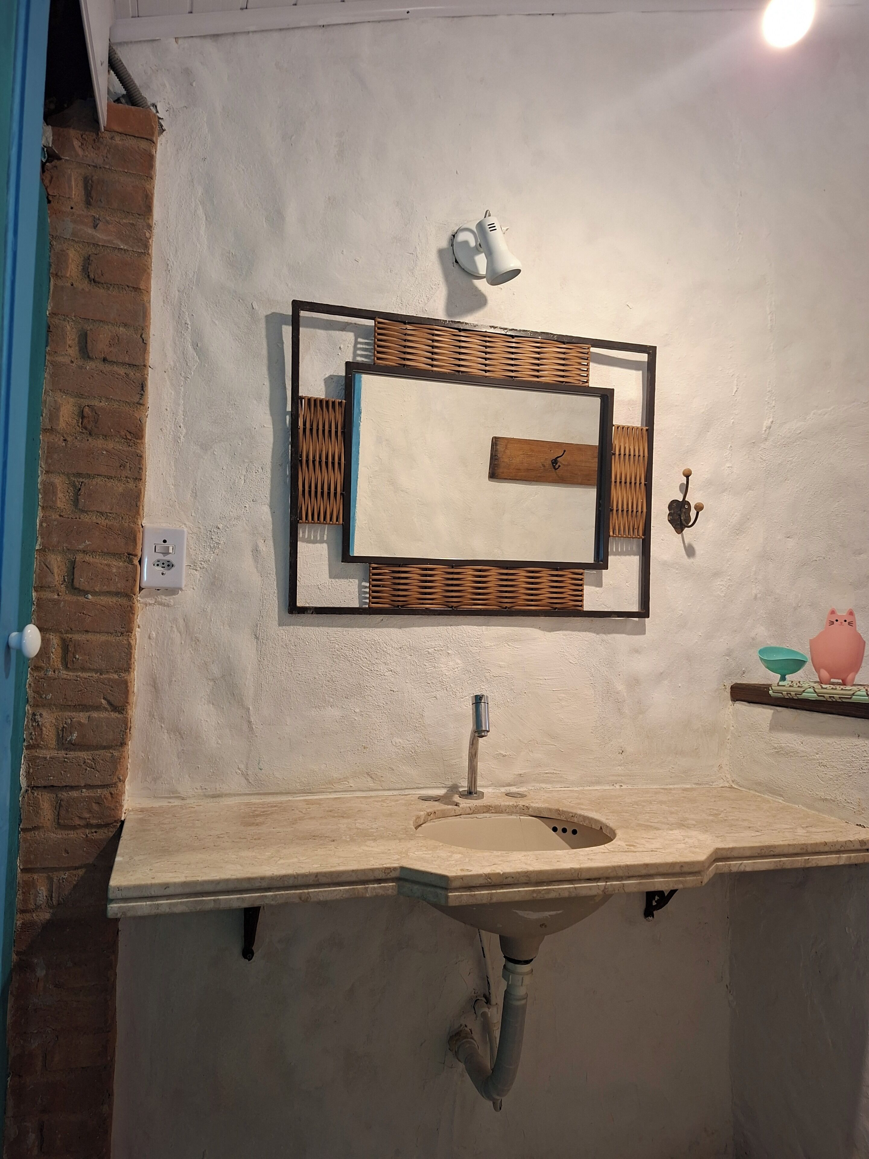 A bathroom with a white sink, a mirror, and a wall-mounted light fixture.