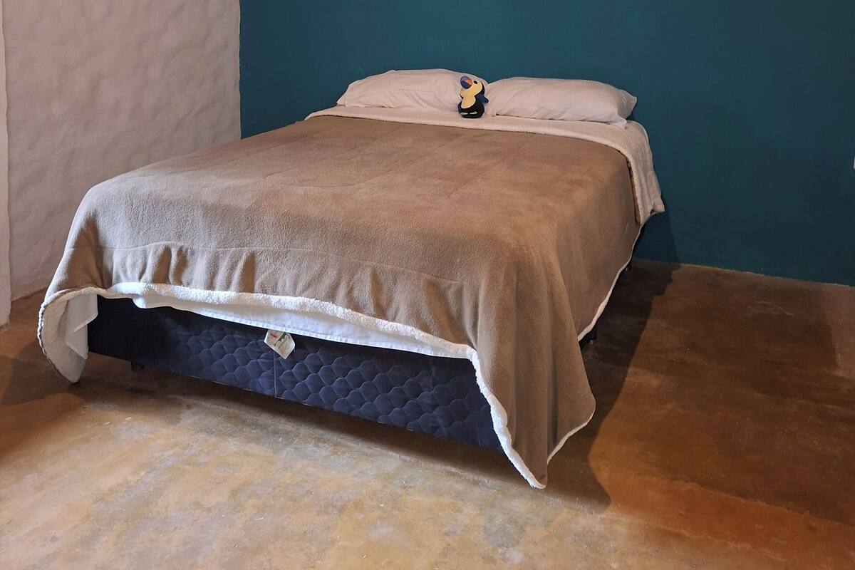 Een slaapkamer met een bed, een nachtkastje met een lamp en een blauwe accentmuur.
