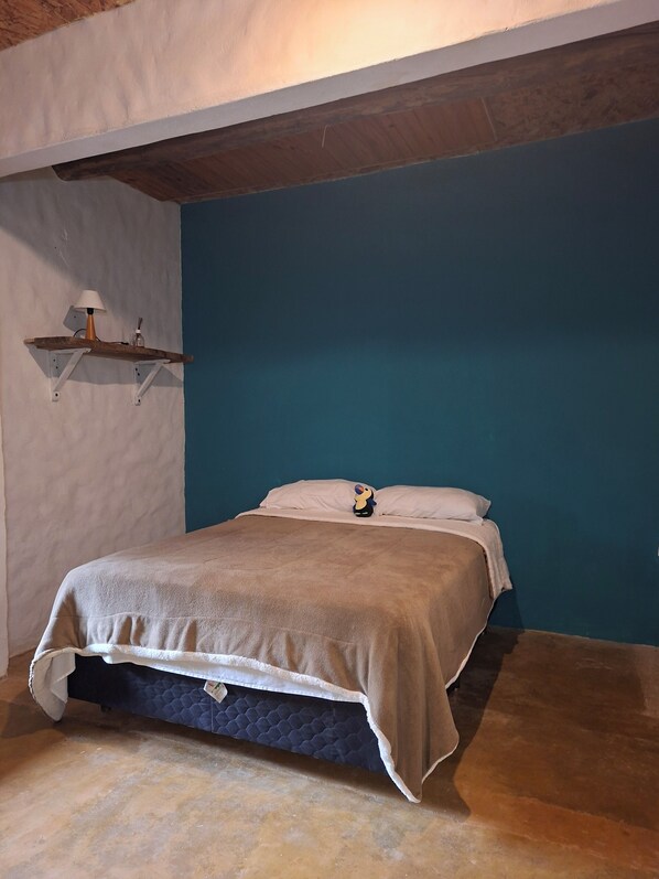 Un dormitorio con cama, una mesita de noche con lámpara y una pared de acento azul.