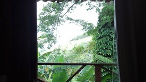 An open wooden door leading to a balcony with a view of lush greenery and a wooden railing. - Hotel fazenda casa mato  (Taubate)