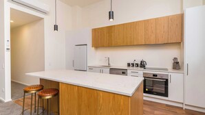 Eine moderne Küche mit Kochinsel, Holdschränken, einem eingebauten Backofen und zwei Barhocker.