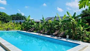 A swimming pool with lounge chairs and tropical plants. - Rocky Mountain Ecolodge (Ninh Binh)