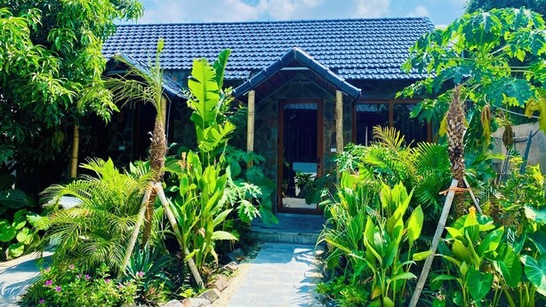 A traditional house with a tiled roof, surrounded by lush greenery and a stone pathway leading to the entrance. - Rocky Mountain Ecolodge (Ninh Binh)