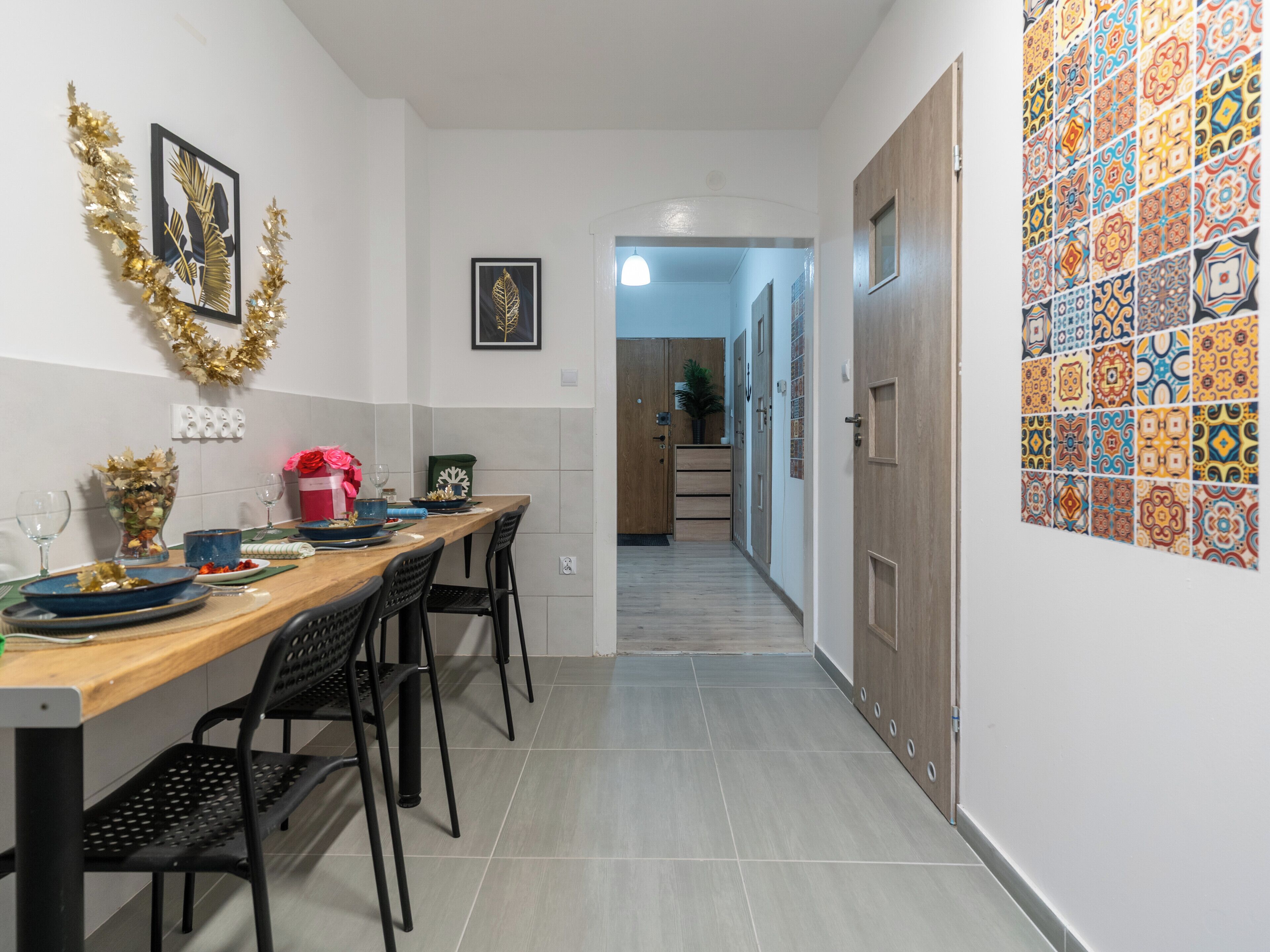Un couloir avec une table à manger en bois, mise pour quatre personnes, des chaises et une guirlande décorative accrochée au mur.