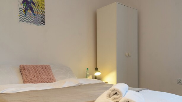 Een hotelkamer met een bed, een kledingkast, een nachtkastje met lamp en een decoratie aan de muur.