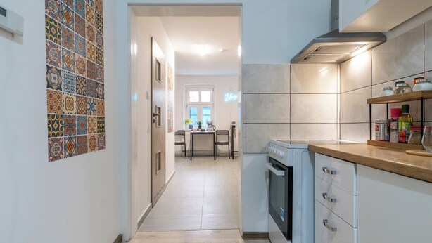 Een moderne keuken met een centraal eiland, witte kastjes en een betegelde spatwand.