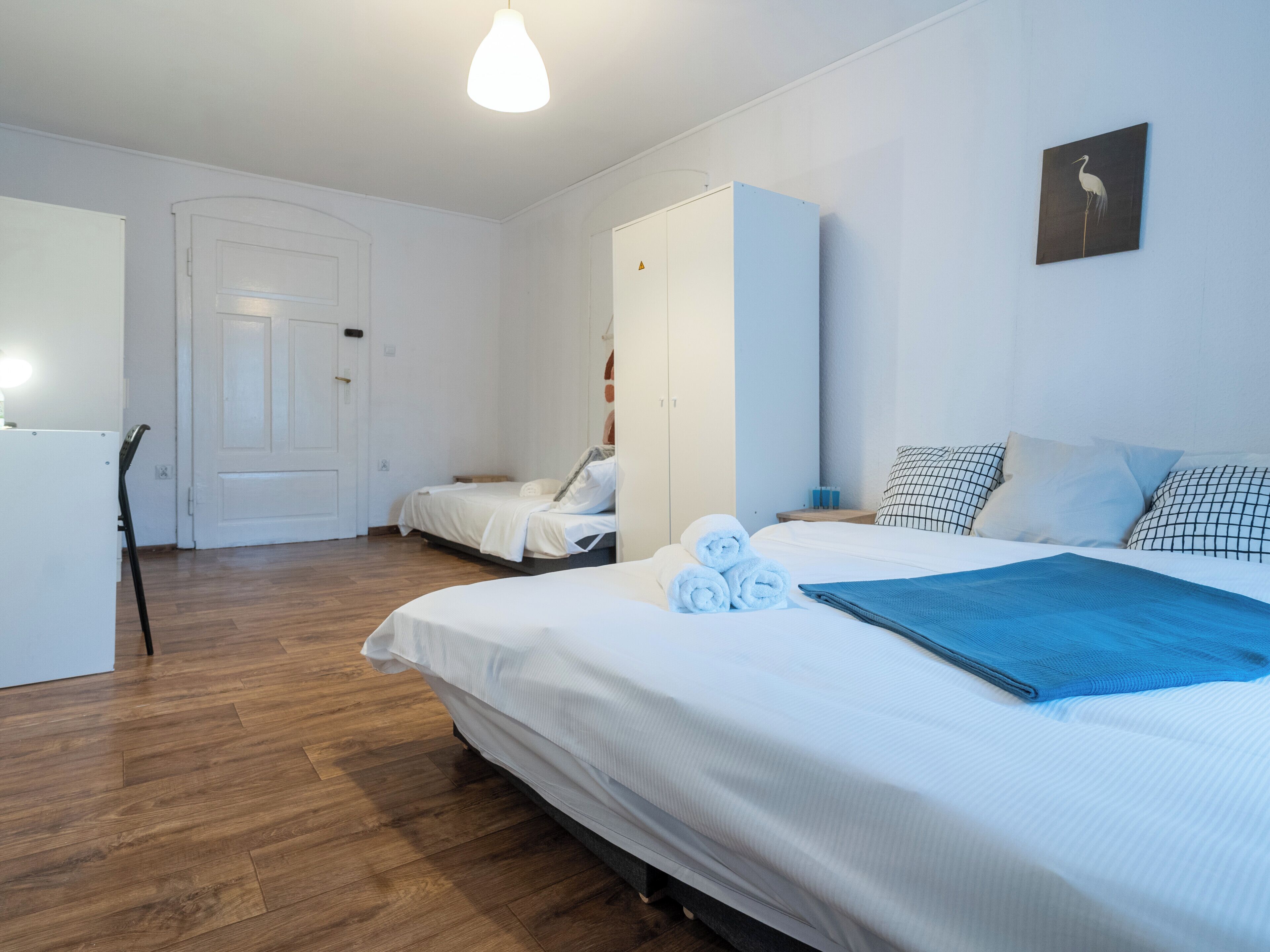 A hotel room with a bed, a desk, and a wardrobe.