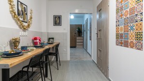 A hallway with a wooden dining table set for four, chairs, and a decorative garland on the wall.