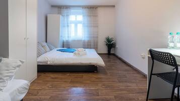 Ein Schlafzimmer mit Bett, Schreibtisch, Stuhl, Kleiderschrank und einem Fenster mit Vorhängen.