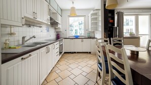 Une cuisine moderne avec des meubles blancs, un plan de travail foncé et un coin repas comprenant une table et des chaises en bois.