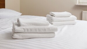 Un lit bien fait, avec du linge de lit blanc et des serviettes pliées.