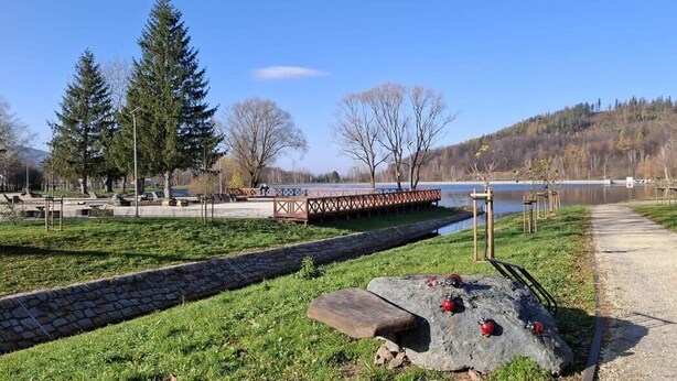 A park with a stone pathway, a wooden bench, and a small bridge over a body of water. - Kowary Forest Apartment near Karpacz (Kowary)