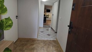 A hallway with a tiled floor, a black mat at the entrance, and a wooden door on the right. - Kowary Forest Apartment near Karpacz (Kowary)