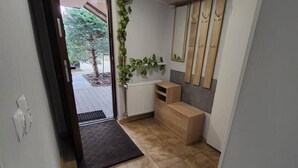 A hallway with a tiled floor, a radiator, a wooden bench, a mirror, and a door leading outside. - Kowary Forest Apartment near Karpacz (Kowary)