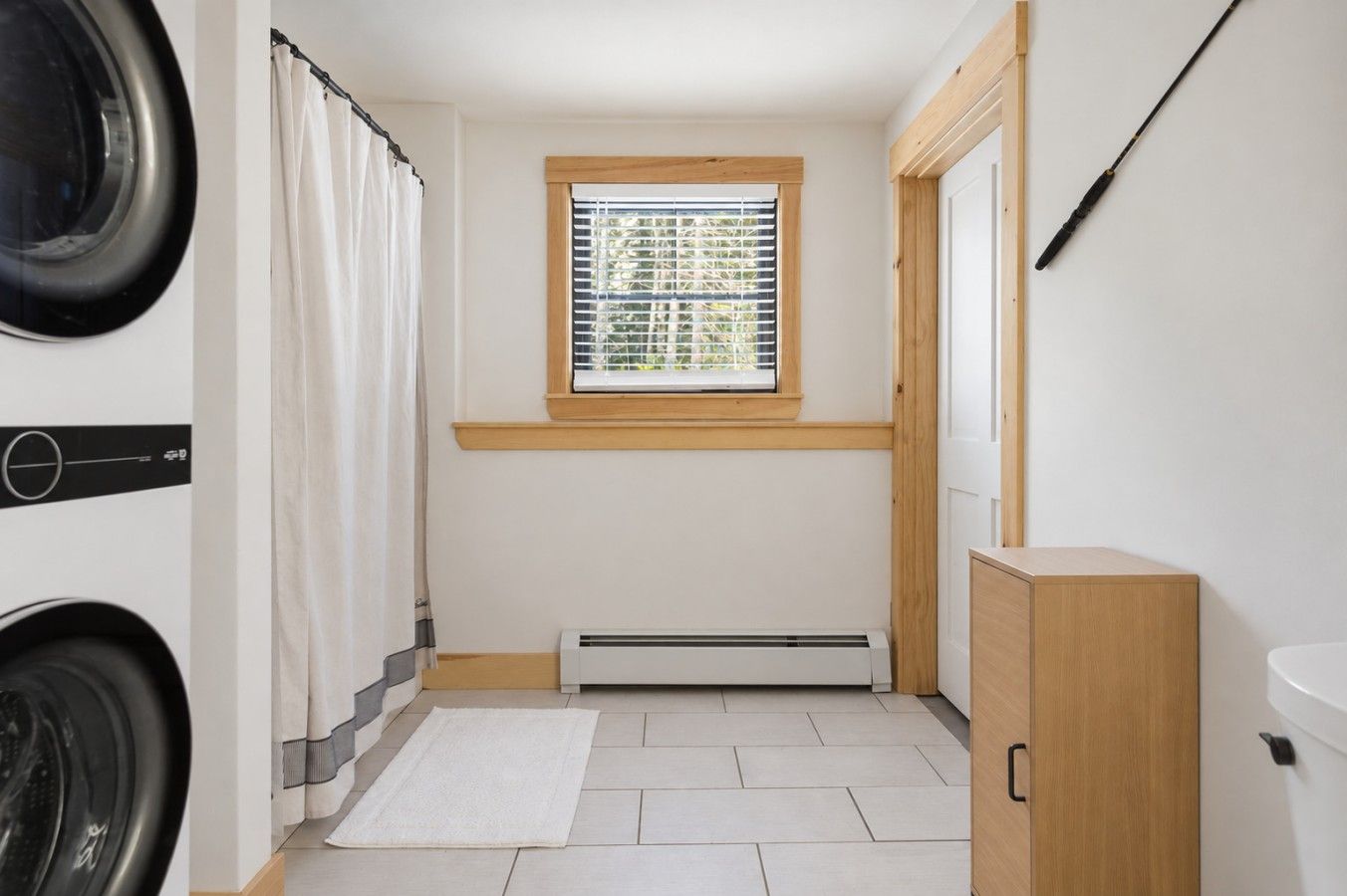 A laundry room with a washing machine, dryer, and a window with blinds.