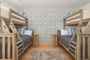 A room with bunk beds, a small stool, and a patterned wallpaper. - Ninth Peak | Golf and Spa Retreat with Trails, Hot Tub & Sauna (Bethel)