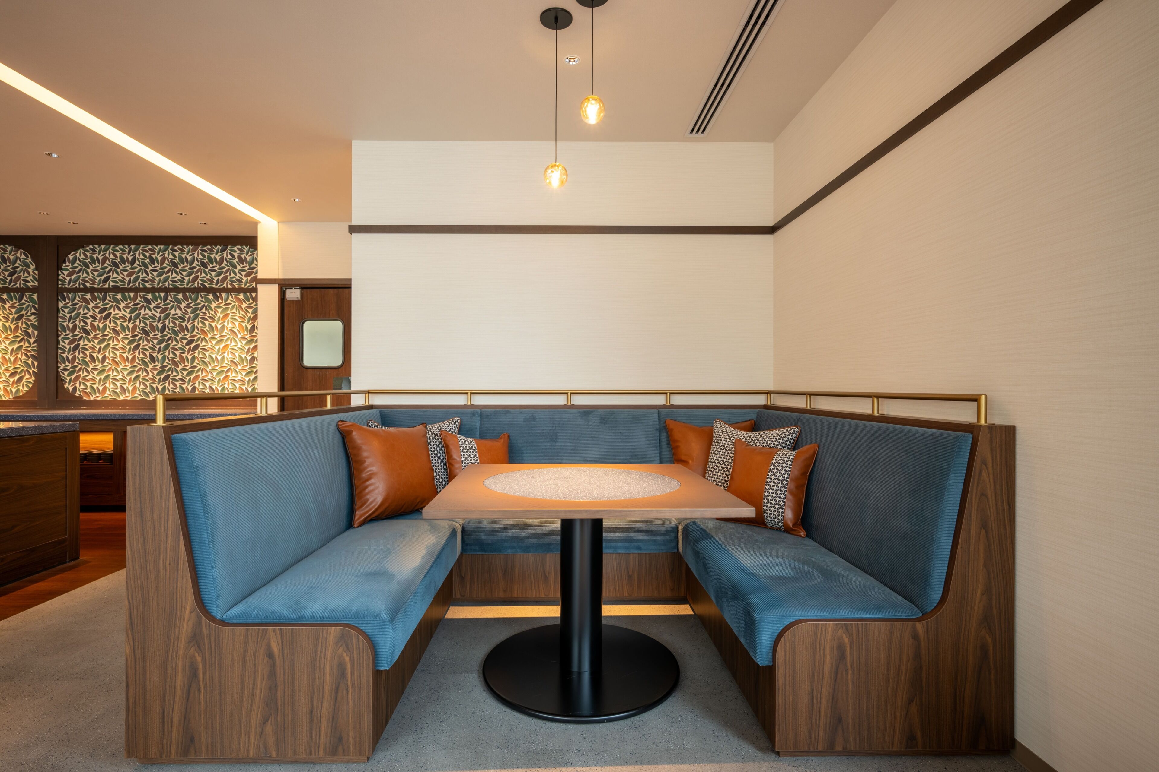 A modern seating area with a round table, cushioned benches, and a decorative wall.