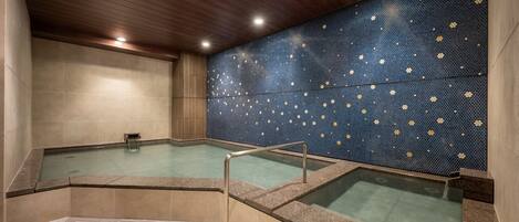 Un área de spa con dos jacuzzis, techo de madera y pared azul con diseños florales.