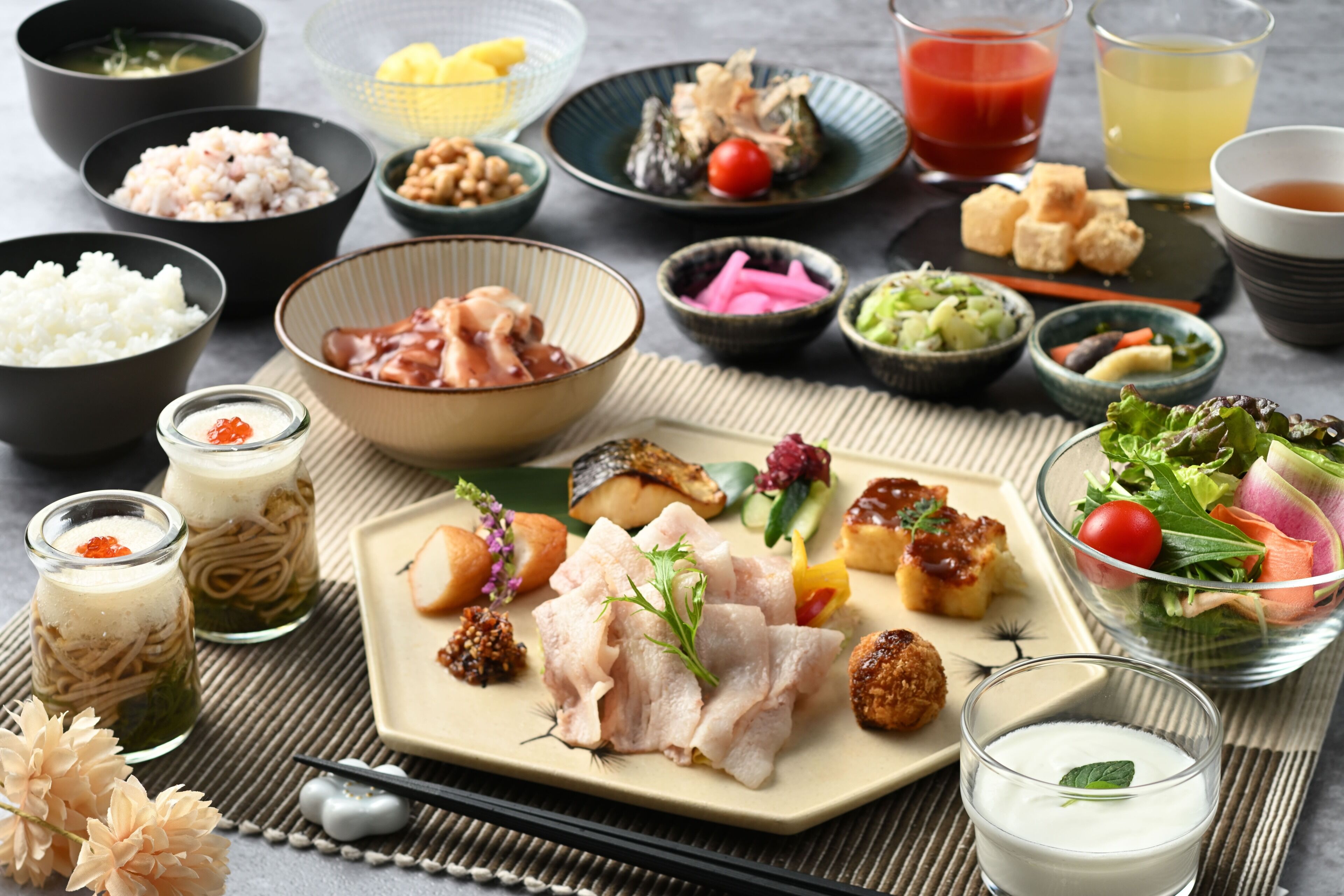 A variety of dishes and beverages on a table, including rice, fish, and vegetables.