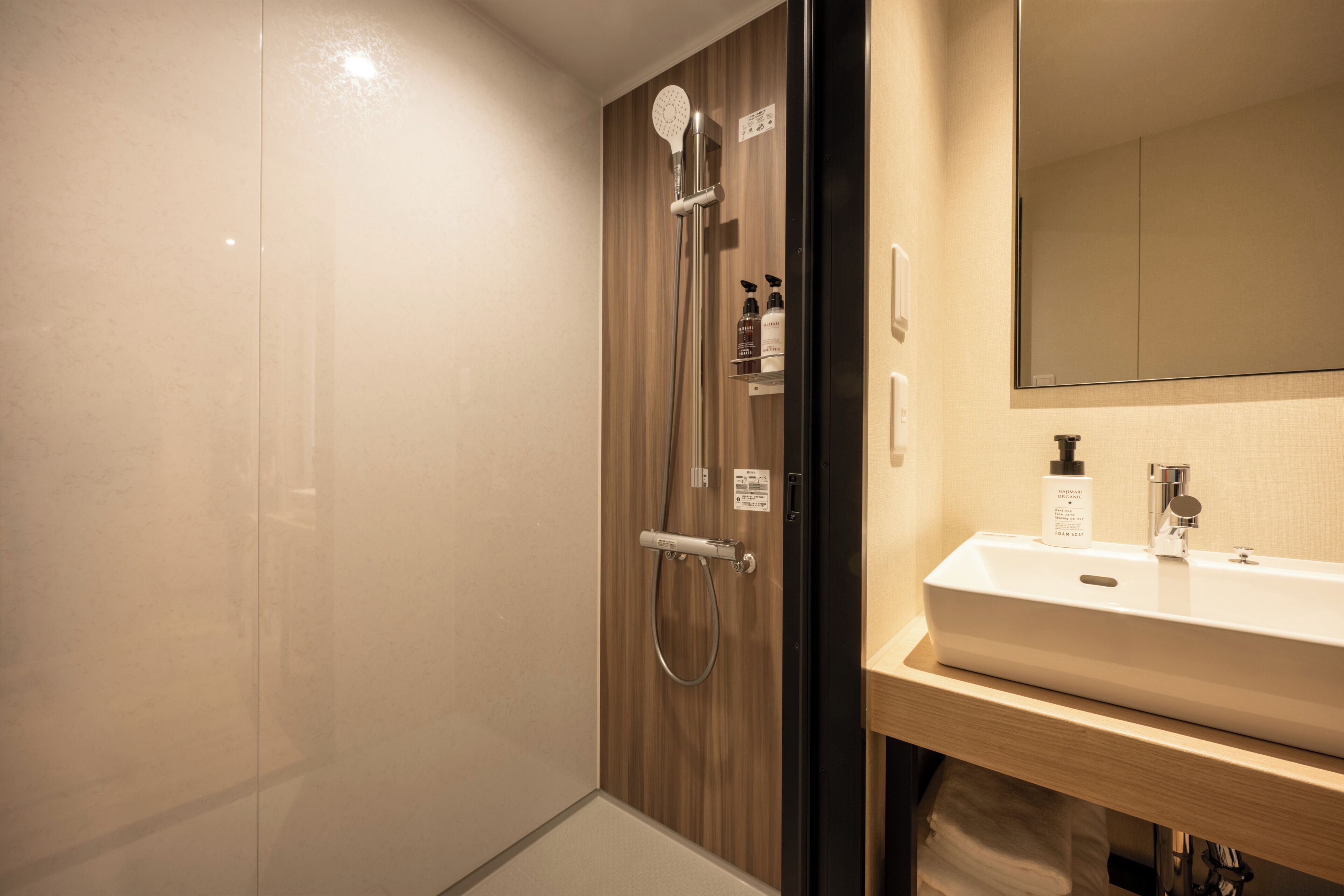 A modern bathroom with a glass shower enclosure, a white sink, and a wooden vanity.