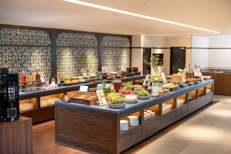 A buffet with various food items, a coffee machine, and a plant.