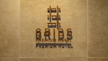 Un logo avec le texte « GRIDS PREMIUM HOTEL » sur un fond texturé.