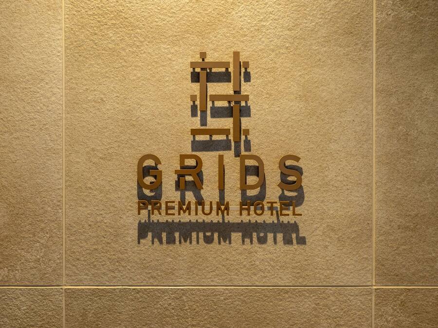 Un logo avec le texte « GRIDS PREMIUM HOTEL » sur un fond texturé.