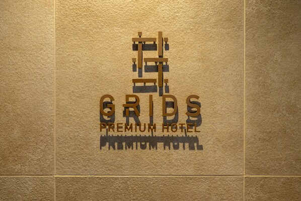 Un logo avec le texte « GRIDS PREMIUM HOTEL » sur un fond texturé.